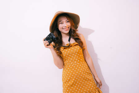 portrait of smiling young girl in hat with camera posing isolated on a pastel backgroundの写真素材
