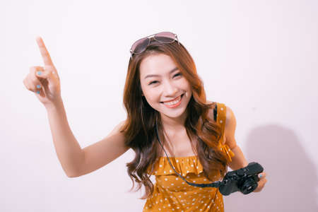 Stylish smiling woman posing with retro camera on pink background.の写真素材