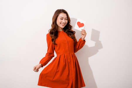 Young woman is reading Valentine card, isolated over whiteの写真素材