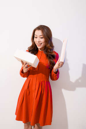 Happy amazed retro styled woman with curly hair in red dress opened present over white backgroundの写真素材