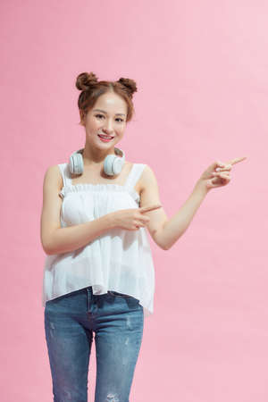 Beautiful asian woman smiling and looking at the camera pointing with fingers to the side.の写真素材