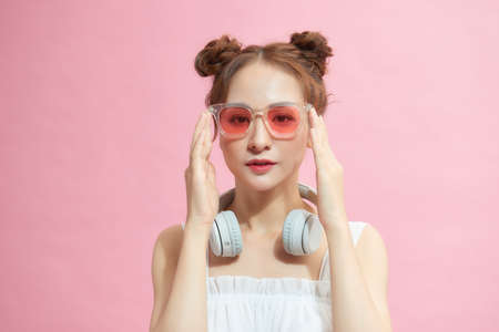 Photo of young woman happy positive smile hand touch sunglass cool isolated over pink color backgroundの写真素材