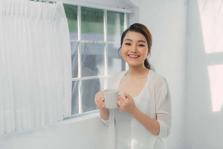 woman in her living room drinking holding a coffee tea mugの写真素材
