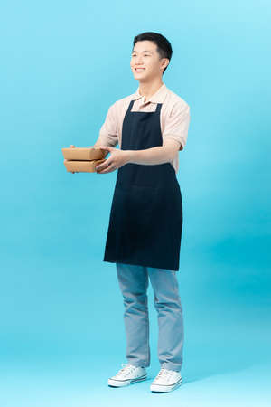 An employee in an apron, takes a fast delivery in a corrugated cardboard box from the courierの写真素材