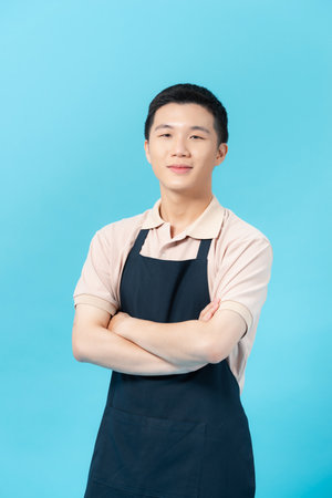 Young man wearing apron on color backgroundの写真素材