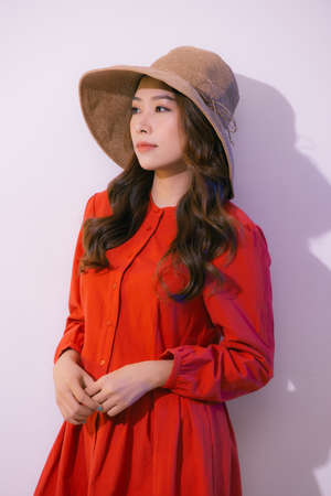 Portrait of an Asian woman wearing a wide-brimmed hat and summer clothes isolated on pink backgroundの写真素材