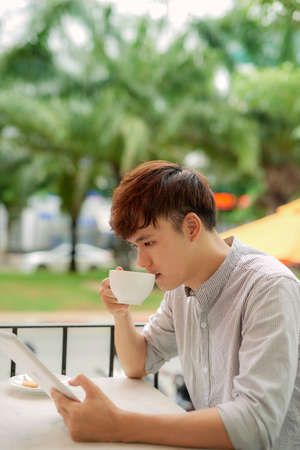 portrait of a happy man holding tablet sitting in a coffee shopの写真素材