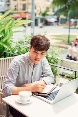 Young freelancer working on laptop in coffeeの写真素材