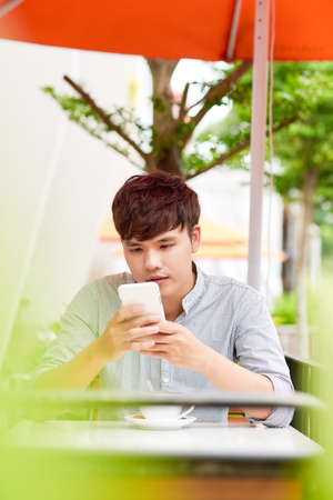 Young man in coffee shop talking on the phone. Outdoorsの写真素材