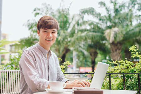 Young man reading information on smartphone when working in cafeの写真素材