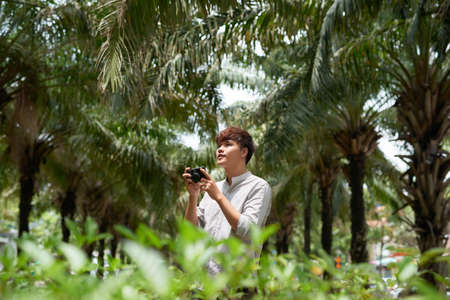 Young asian tourist man smiling happy using vintage camera at the city.の写真素材