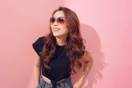 Portrait of smiling beautiful girl in sunglasses against of pink backgroundの写真素材