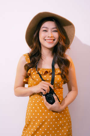 Pretty young tourist woman in summer white dress hat with photo camera isolated on pink background.の写真素材
