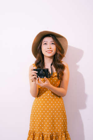 Stylish smiling woman posing with retro camera on pink background.の写真素材