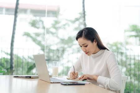 A young female student sitting at the table, using laptop when studying.の写真素材