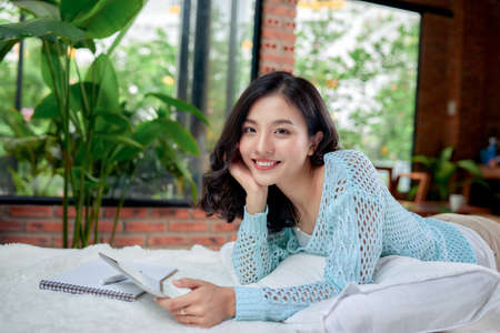 sian female student doing homework in bedの写真素材