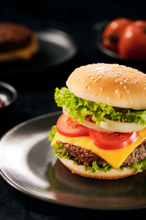 Fresh Tasty burger on cutting board with with french fries, ketchup and cola in glass over black backgroundの写真素材