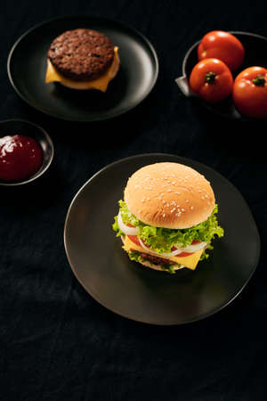 Hamburger with beef meat burger and fresh vegetables on dark background. Tasty fast foodの写真素材