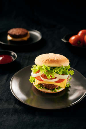 Hamburger with beef meat burger and fresh vegetables on dark background. Tasty fast foodの写真素材