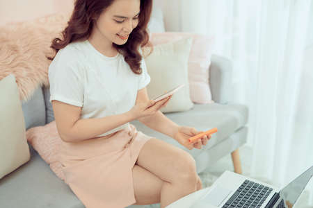 Pretty woman holding phone shooting new lipstick in home officeの写真素材