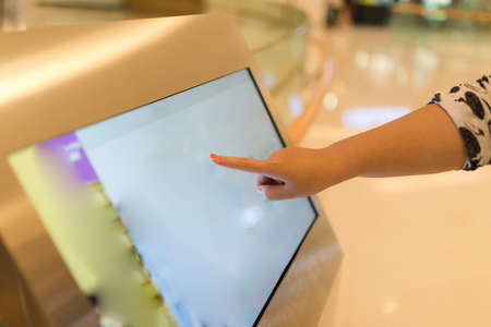 Close-up of female hand on touch screen information counter in shopping mall.の写真素材
