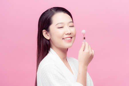 Woman caring of her beauty face with cosmetic tool. Skin care concept. Girl holds item for makeup.の写真素材