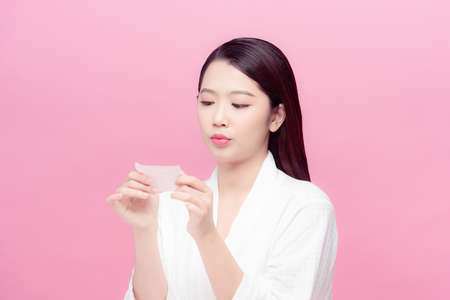 Woman using facial oil blotting paper.の写真素材