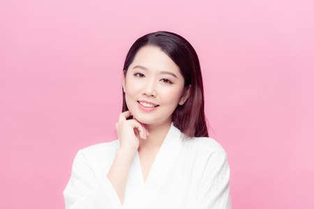 Beautiful young Asian woman touching soft cheek and smile with clean and fresh skin.の写真素材