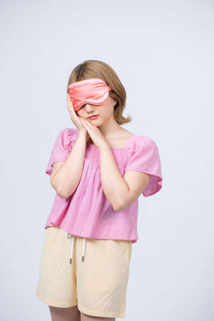 Portrait of Young beautiful woman sleeping with eye mask on white background.の写真素材