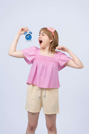 Oversleeping woman holding alarm clockの写真素材