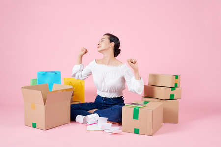 Woman is stretching while preparing products in the packaging box to prepare for delivery to customers.の写真素材