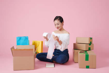Happy young asian woman startup small business freelance sitting on floor with parcel boxの写真素材