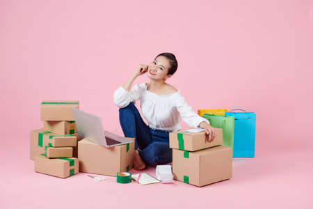 Young Asian small business owner with smartphone, online marketing packaging box delivery, SME e-commerce conceptの写真素材