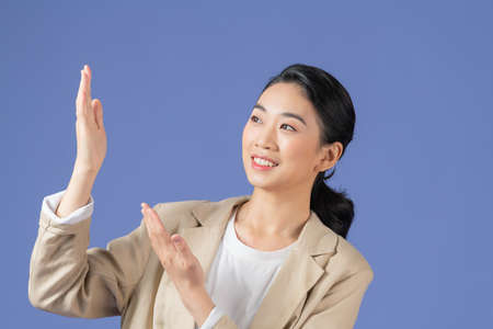 Portrait of beautiful young woman pointing up over purple background.の写真素材
