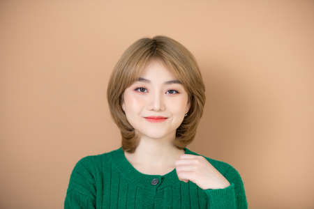 Young modern girl wearing a green wool winter sweater happy face smiling, looking at the camera. positive person.の写真素材