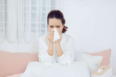 Sick woman with seasonal infections, flu, allergy lying in bedの写真素材