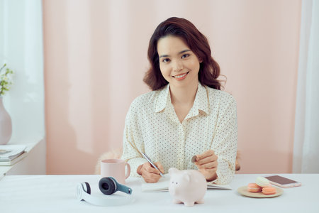 plan finance and savings money.young women put money coin in piggybank and calculate cost.の写真素材