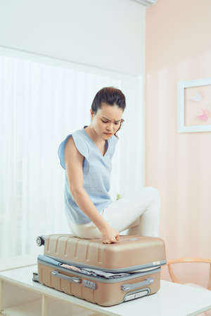 A picture of a woman having problem with packing a suitcaseの写真素材