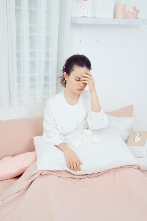 Sick woman with headache sitting under the blanket.の写真素材