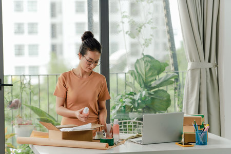 Woman packing cosmetic products in box for courier or poster shipment.の写真素材