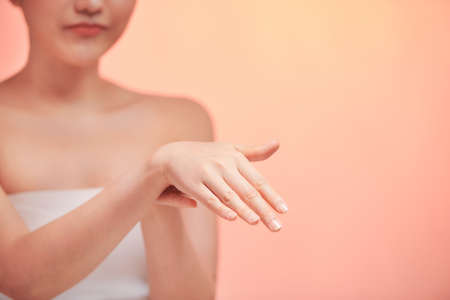 Beautiful young woman applying cosmetic moisturizer on handsの写真素材