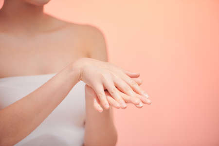 Cropped close up photo of young woman`s hands applying moisturizer cream body oil for smooth effect in spaの写真素材