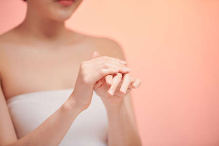 Smiling young woman applies cream on her hands.の写真素材