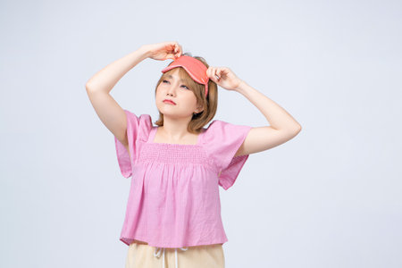 Photo of young attractive girl wake up after sleep isolated on gray backgroundの写真素材