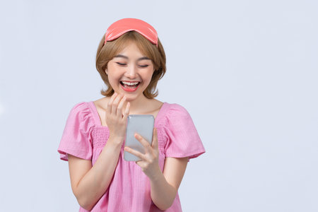 Smiling young girl looking at smartphone screen in the morningの写真素材