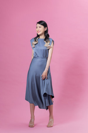 Young smiling woman with trendy dress posing in the studio on pink background.の写真素材