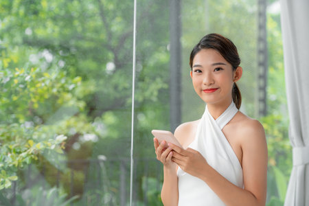 Millennial Korean Woman Shopping Online Or Browsing New App On Mobile Phoneの写真素材