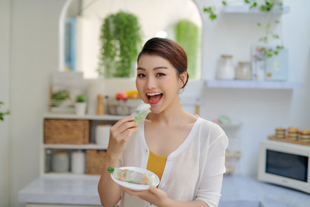 Asian woman eating tasty traditional spring rollsの写真素材