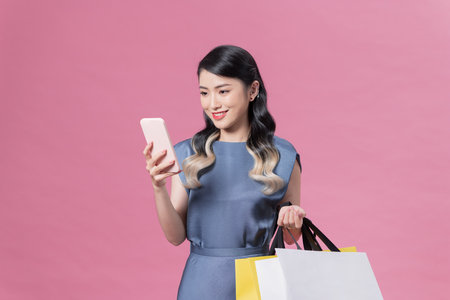 Shopping woman with bags texting message on smartphone while walkingの写真素材