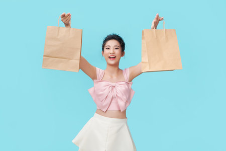 happy shopping young woman show bags - isolated on blue background,の写真素材